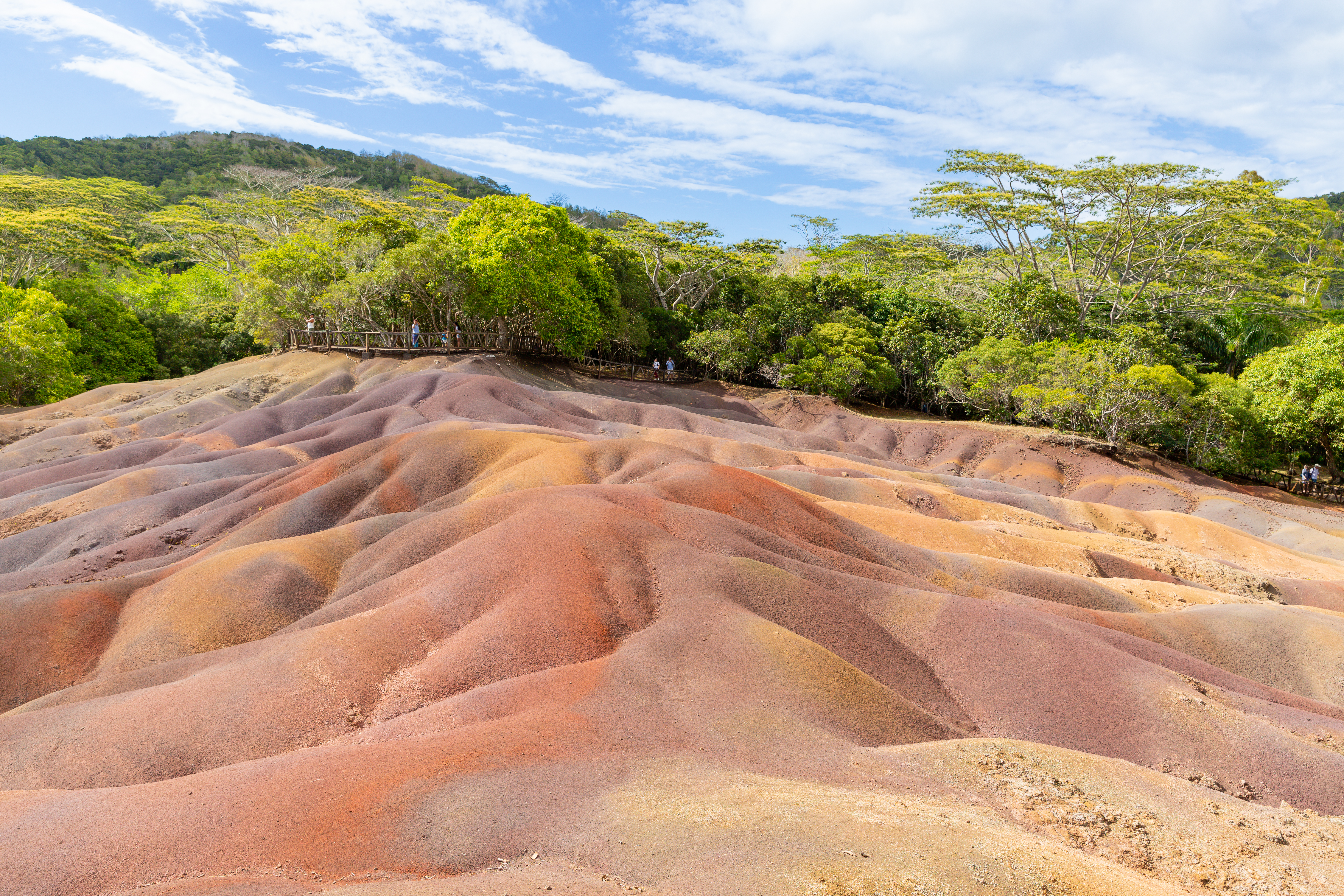 Striped red, brown, violet, and yellow sand dunes at the Seven Coloured Earths geological site in Chamarel, Mauritius