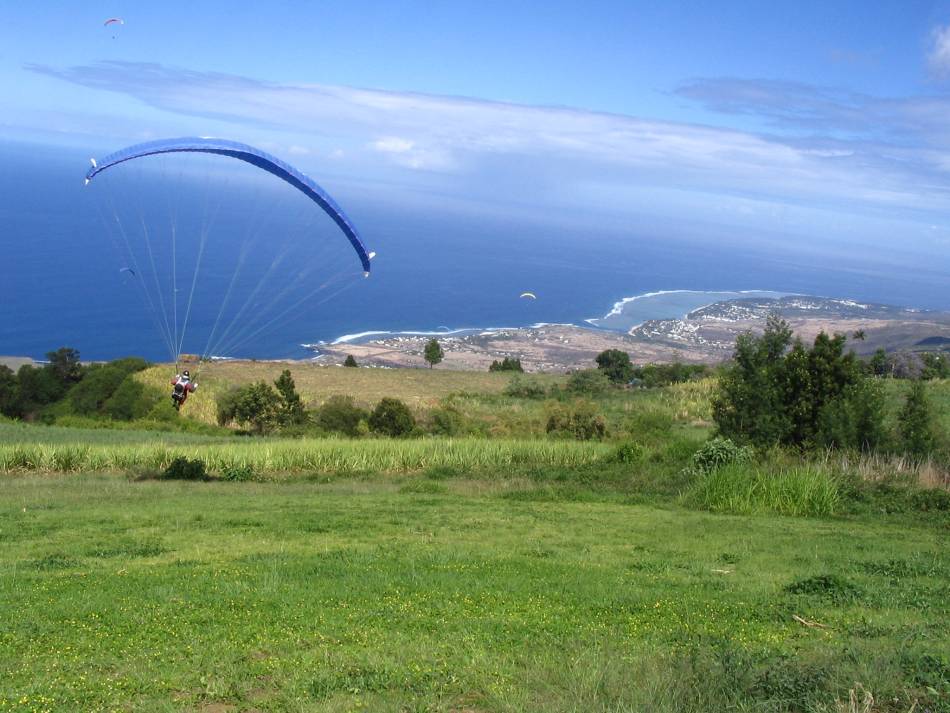 A paraglider launching over Saint-Leu, Réunion, above the coastal lagoon