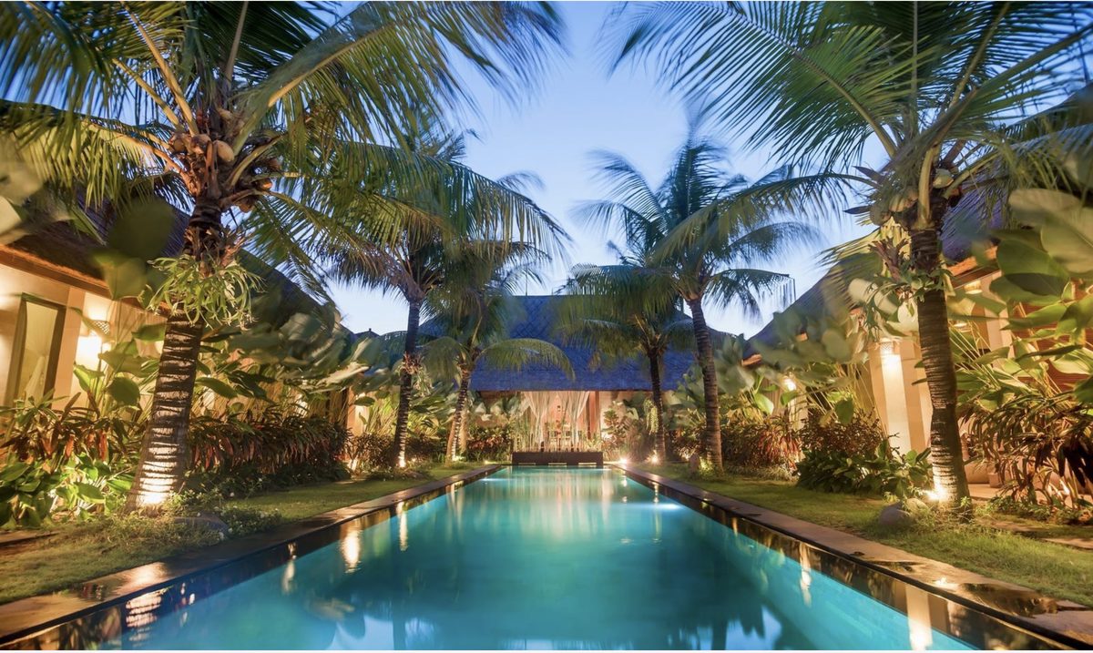 Karmagali Boutique Suites' lap pool at dusk, framed by palm trees