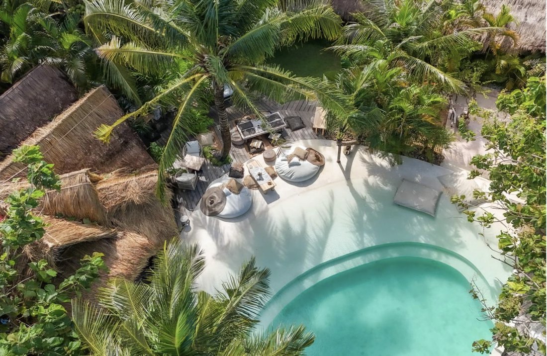 Aerial view of La Cabane's beach-sand pool surrounded by palm trees