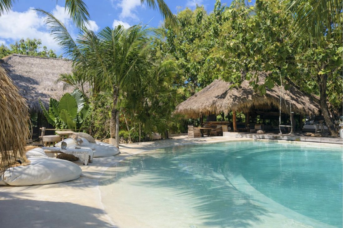 Poolside lounge area with thatched-roof bungalows