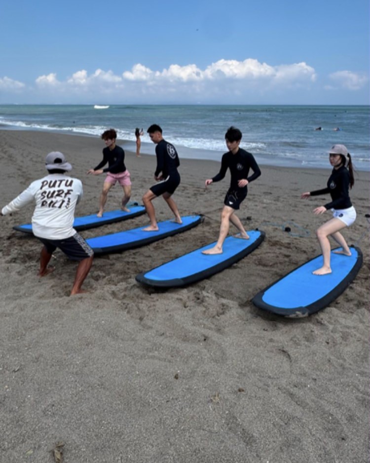Putu coaching a group surf instruction on the beach
