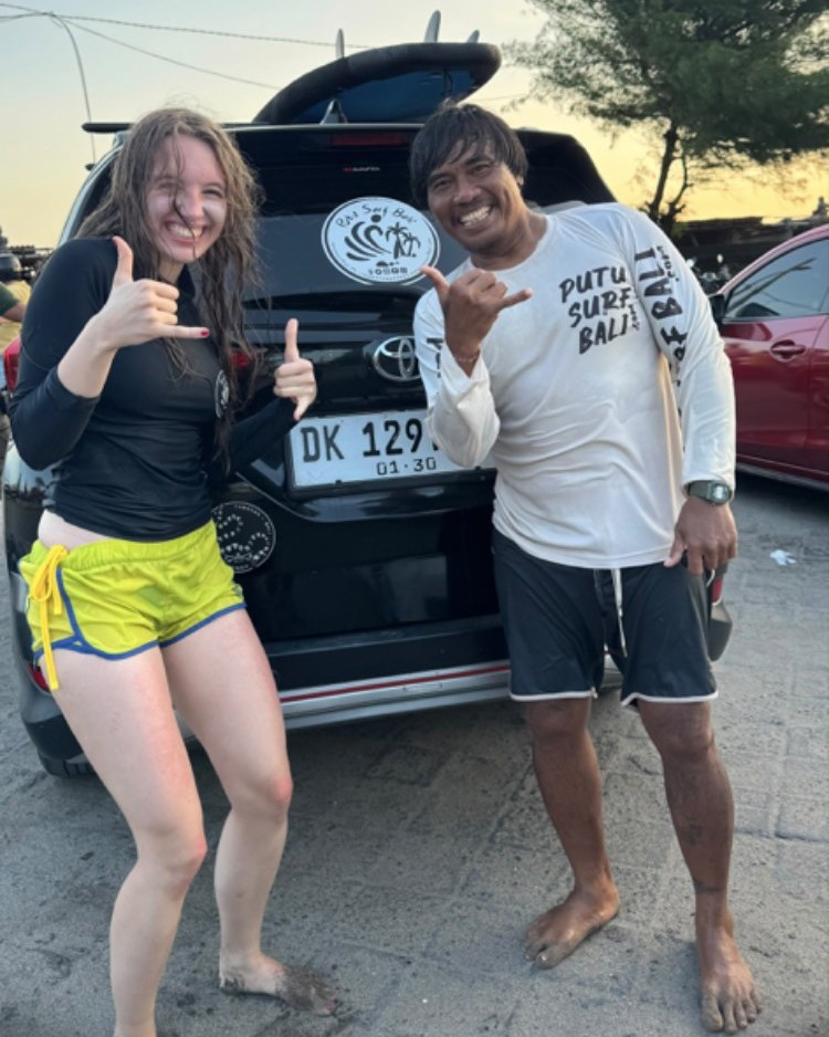Putu with a surf student giving a shaka in front of his surf van