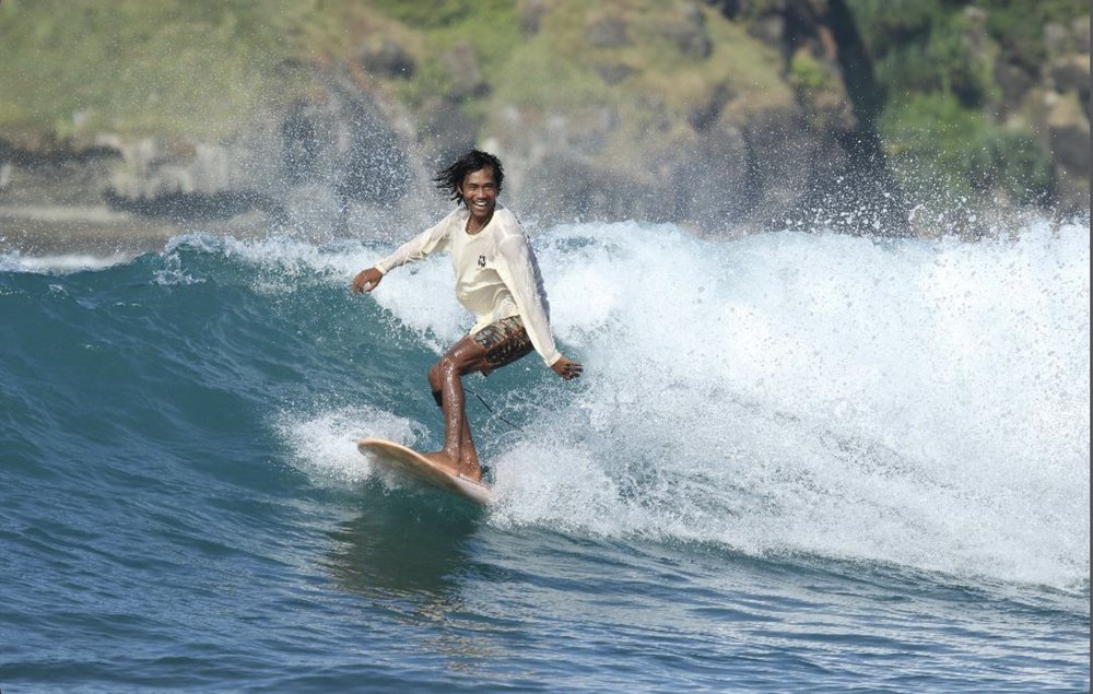 Surf Local Lombok guide riding a wave with a big smile