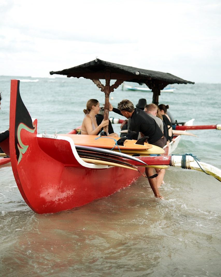 Surfers loading boards onto a boat for a WaveHouse surf trip