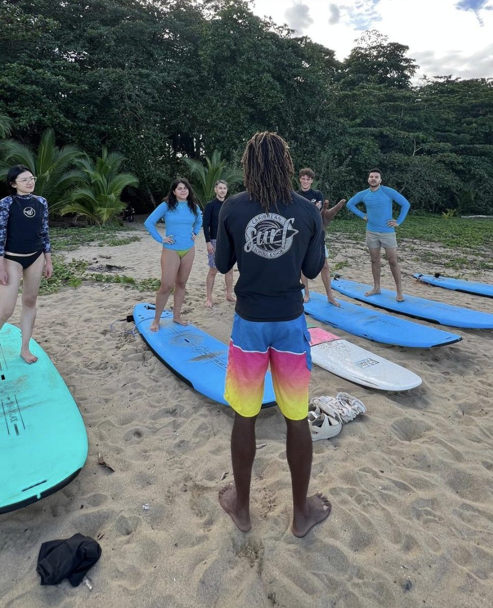 Hershel briefing a group on the beach, wearing a Caribbean Surf School and Shop shirt
