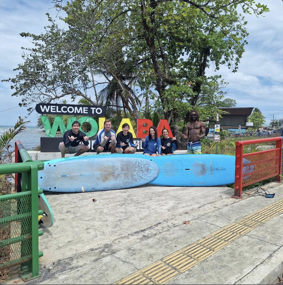 Group with SUP boards at the Welcome to Wolaba sign in Puerto Viejo