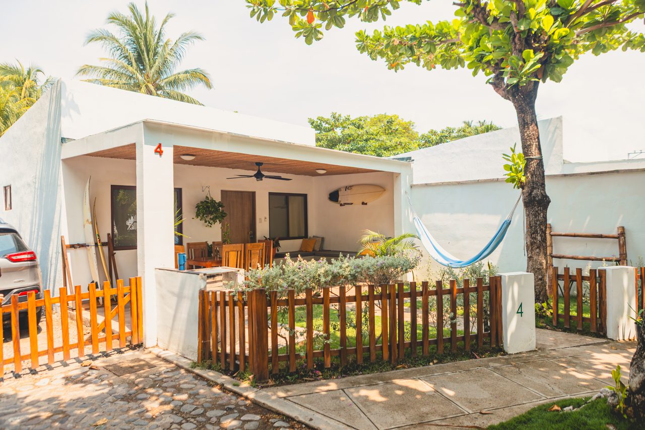 Exterior of Coco Surf's beachfront cabanas with palm trees and a hammock