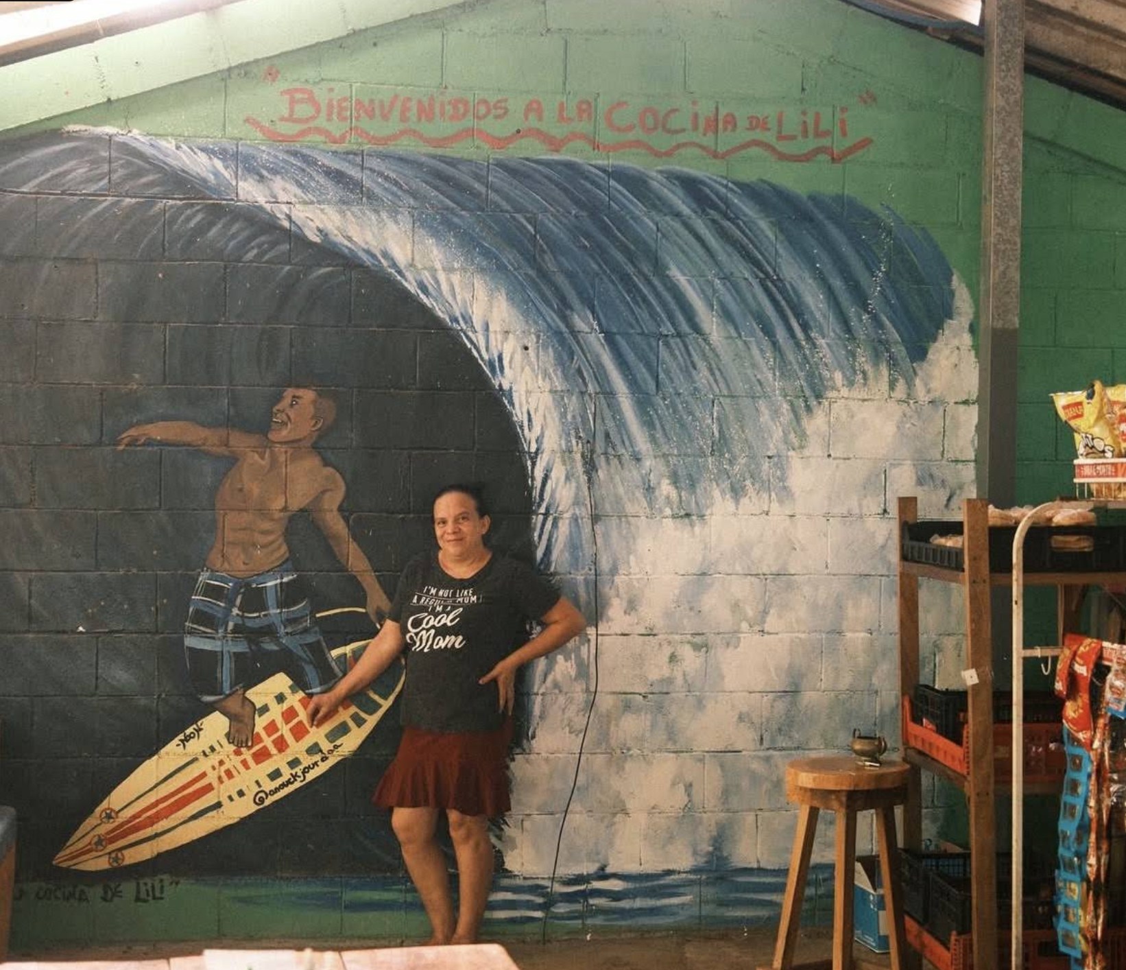 Lili standing in front of the hand-painted surf mural at La Cocina de Lili, Punta Mango