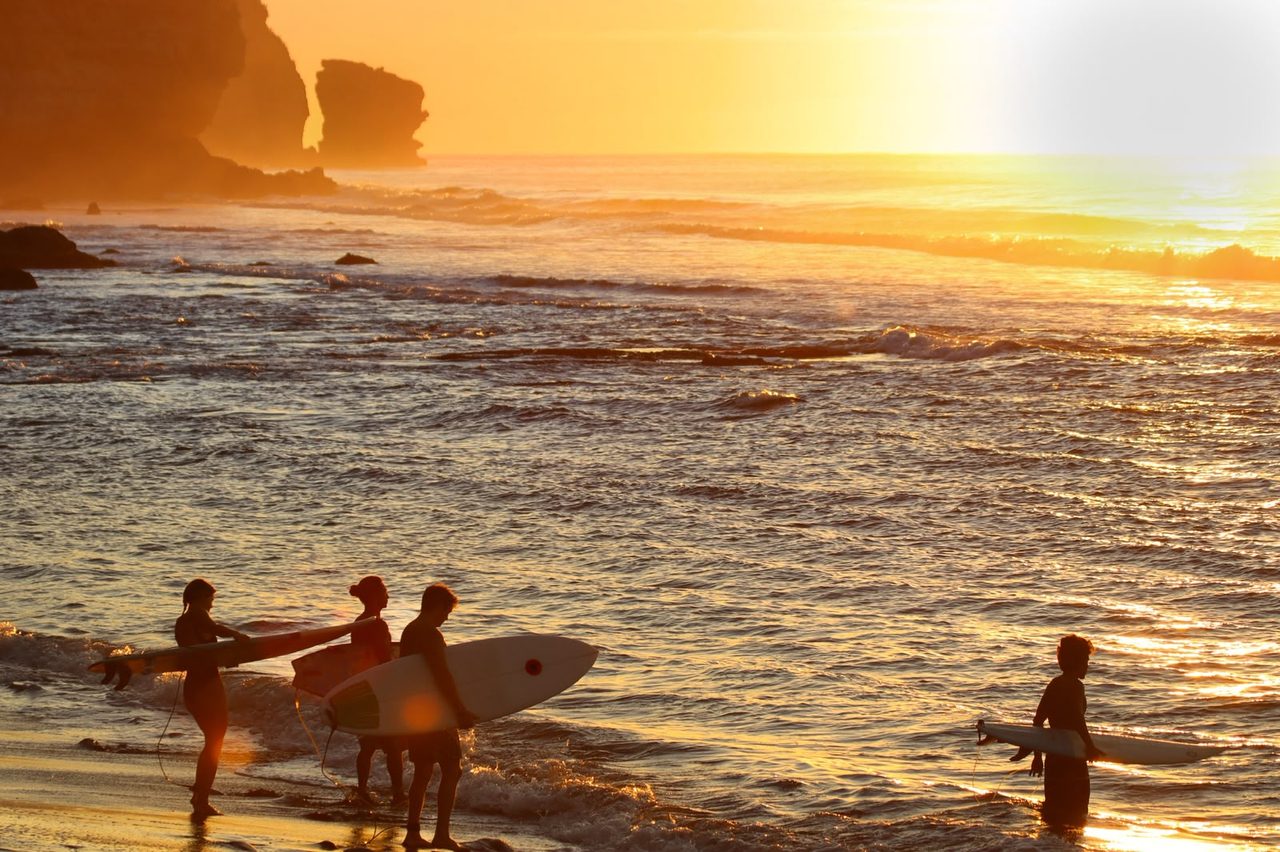 Surfers walking in at sunset with Litoral Surf Trips