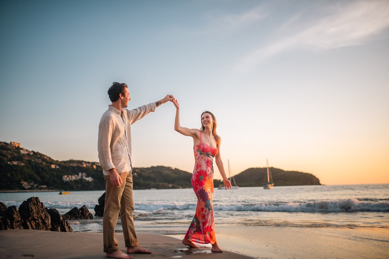 Couple dancing on the beach at sunset, Ixtapa-Zihuatanejo bay in the background