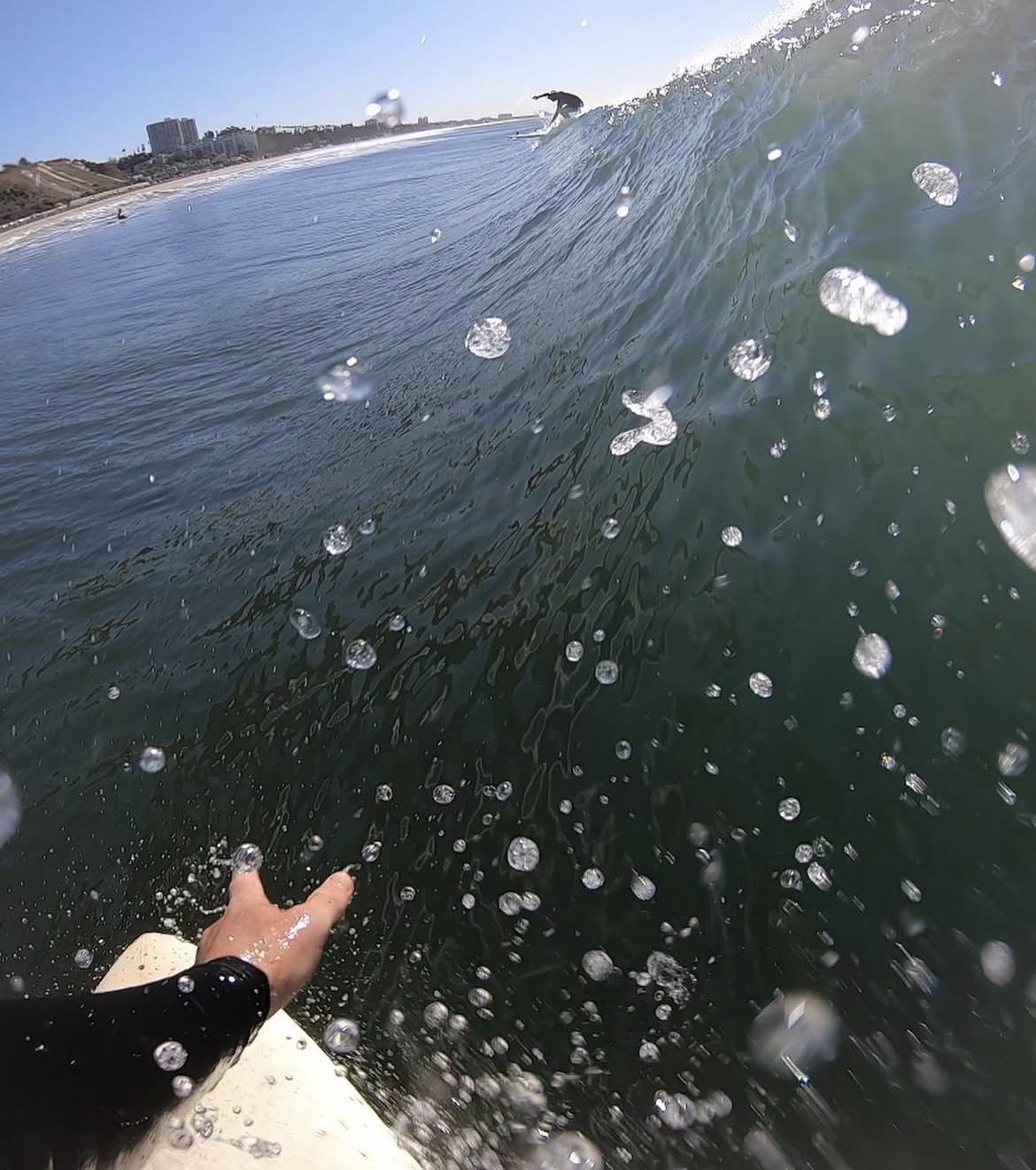 POV shot from the water of a surfer riding a wave off the LA coast