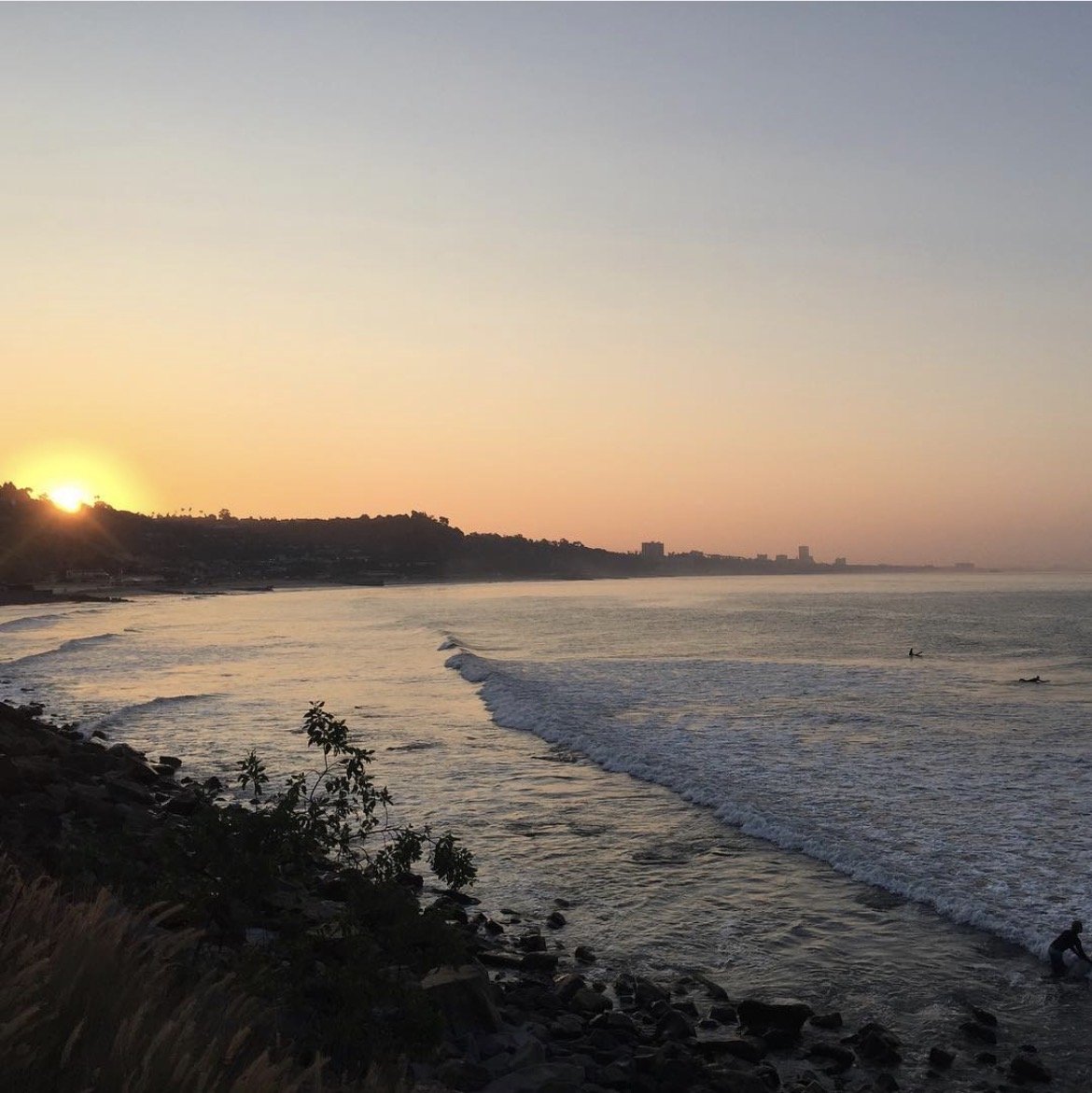Sunset over the LA coastline with surfers in the water