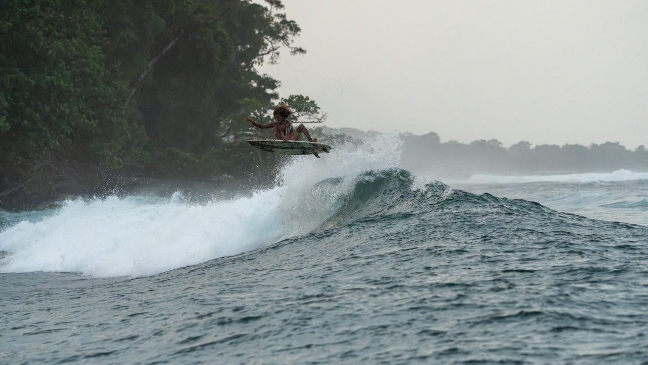 Surfer catching air off a wave breaking along a jungle point, shot by Bocas Is Love