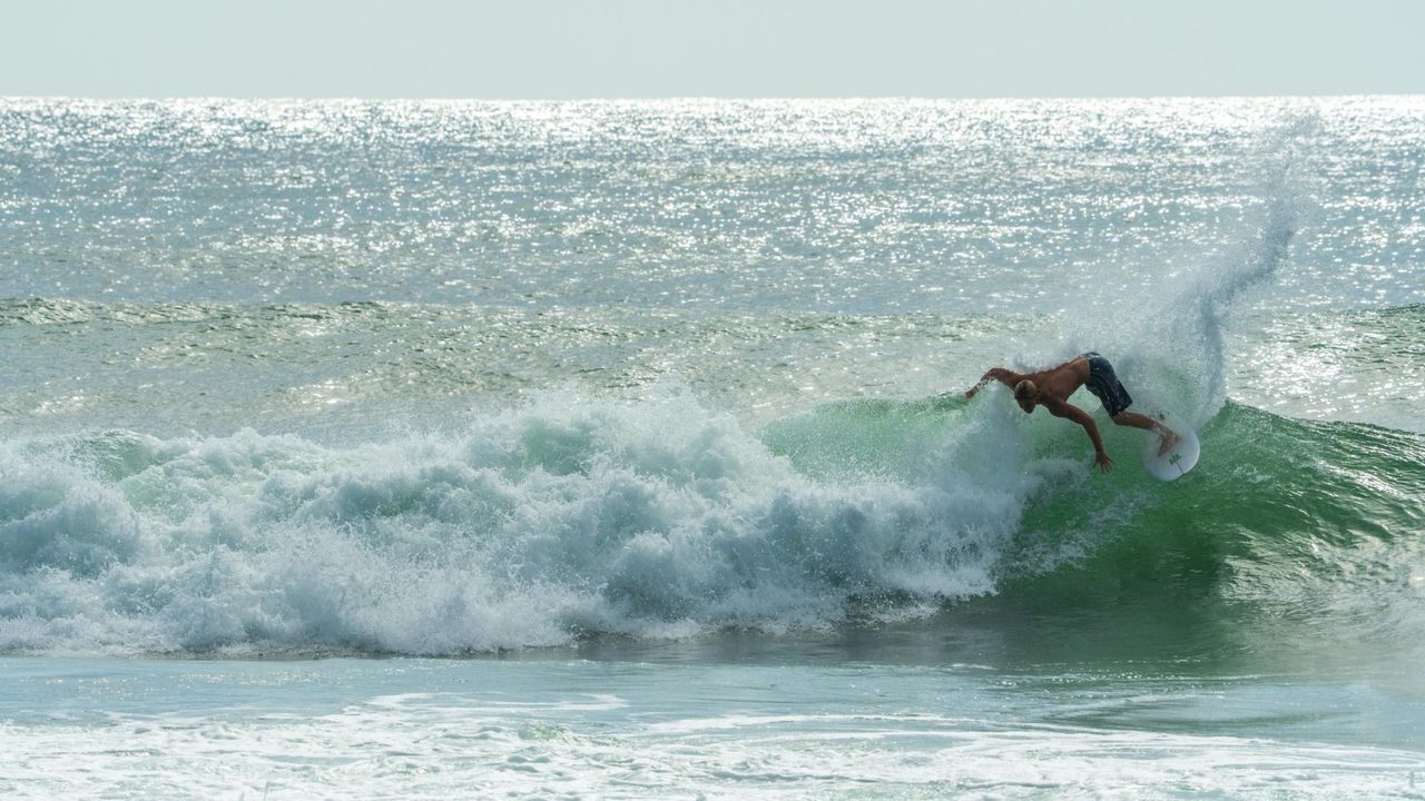 Surfer turning on a backlit, shimmering wave, shot by Bocas Is Love
