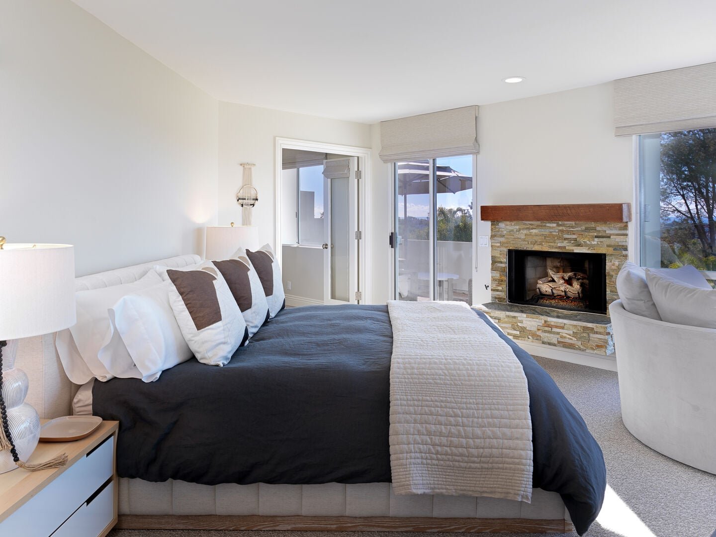 Bedroom with a stone fireplace and balcony access at an Encinitas Haustay home