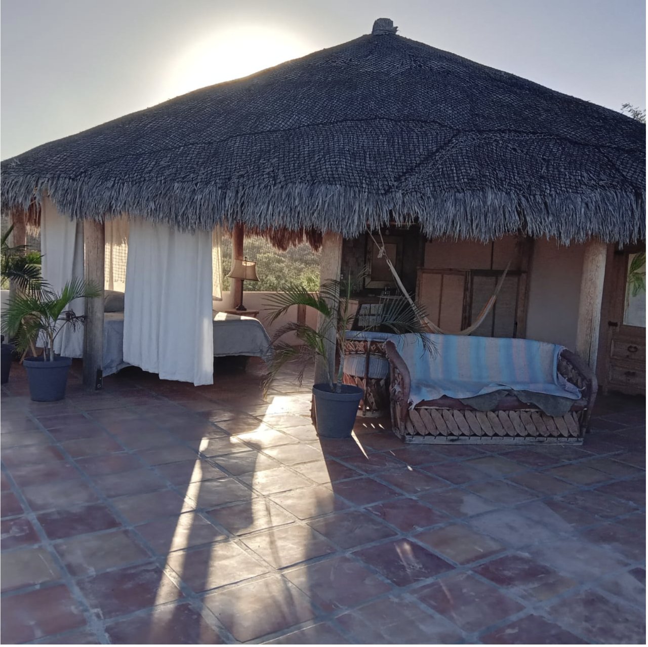 Open-air palapa-roofed penthouse suite with beds and a hammock