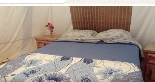 Inside a teepee, bed with nightstands and a reading lamp